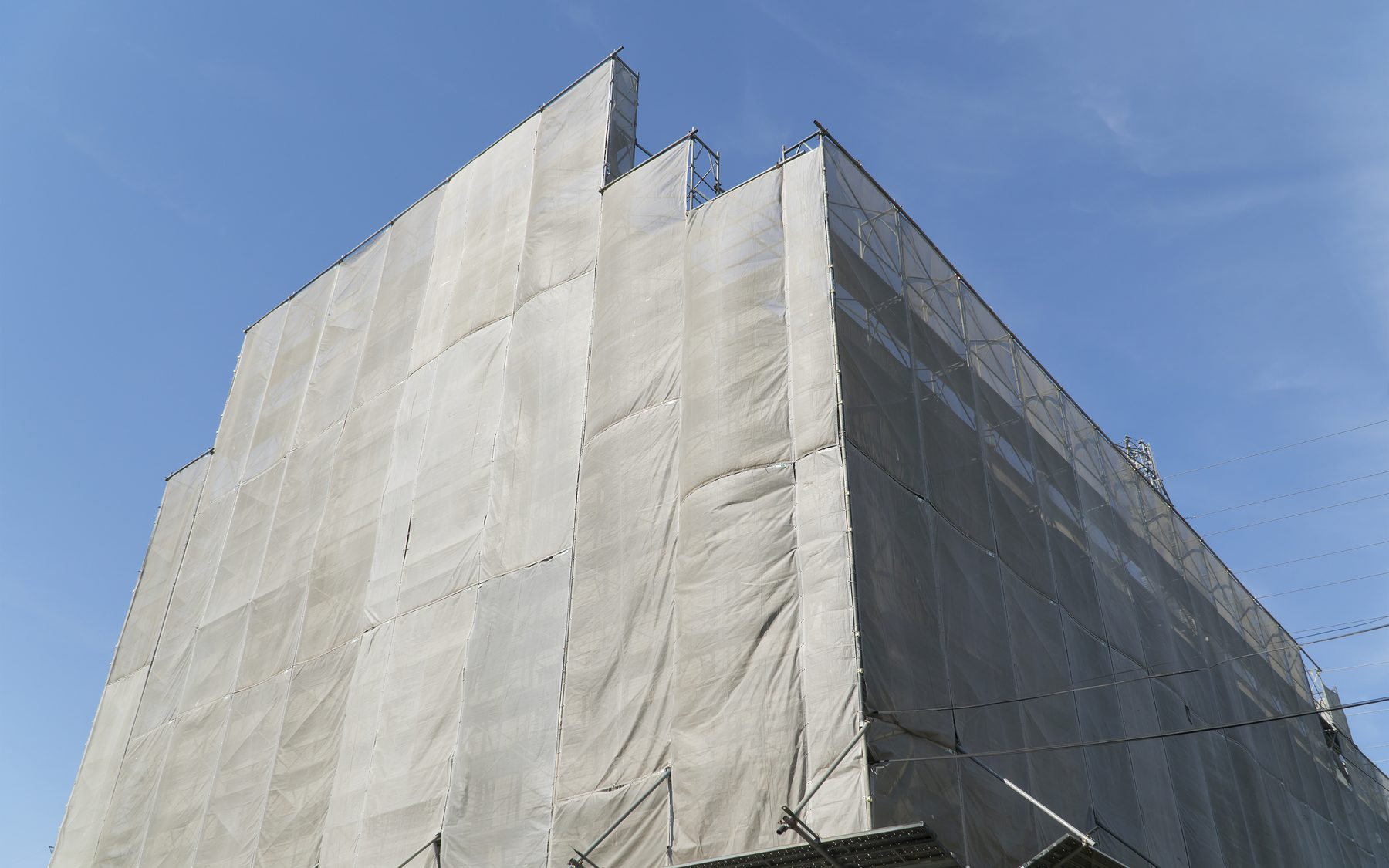足場とメッシュシートで覆われた大規模修繕工事中のマンション